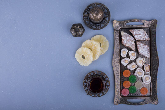 Metallic pastry platter with delights and a glass of tea