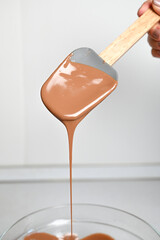 The process of tempering chocolate and making chocolates. Pastry chef using spatula tempering molten chocolate. Vertical
