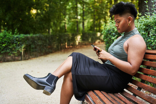 Filipino transgender woman using smartphone on bench