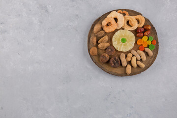 Dry fruits and snacks in wooden platter in the center
