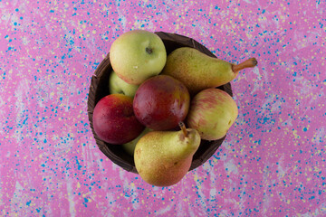 Fruit mix in a wooden bucket on pink background
