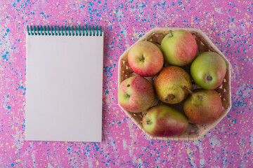 Green pears and apples in a basket with a receipt book aside