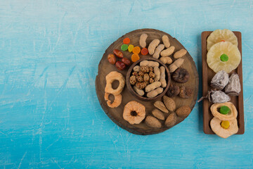 Dry fruits and snacks in wooden platters isolated on blue background