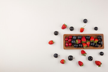 Naklejka na ściany i meble Berry mix on a wooden platter and on the white background