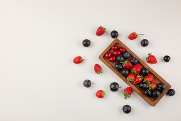 Berry mix on a wooden platter and on the white background in the corner
