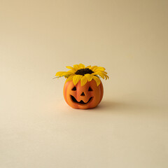 Autumn , halloween 2022. Halloween pumpkin with yellow sunflower  on beige  background. Minimal festive composition.