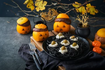 Foto op Plexiglas Halloween party jack-o-lantern chocolate orange cakes against the background of the old forest, branches and leaves. Halloween food concept. Sweets for Halloween celebration. © kasia2003