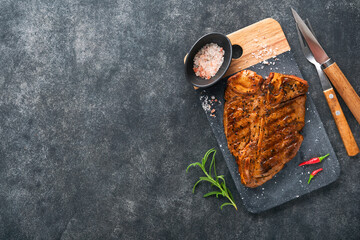 Raw steak t-bone or porterhouse. Steak t-bone or porterhouse in sauce with spices, salt and rosemary on a black ceramic plate on concrete background. Top view. Place for text.