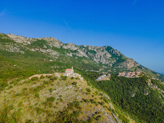Fototapeta na wymiar Panoramic view of the city of Budva, Montenegro. Beautiful view from the mountains to the Adriatic Sea Portrait of a disgruntled girl sitting at a cafe table