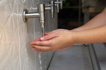 Asian woman opening faucet to wash hands Clean before and after touching food. Soft and selective focus.