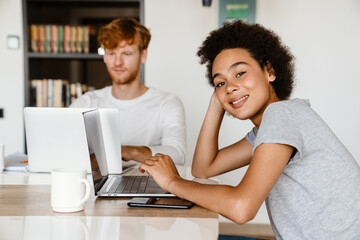 Young couple drinking coffee while using laptops together at home