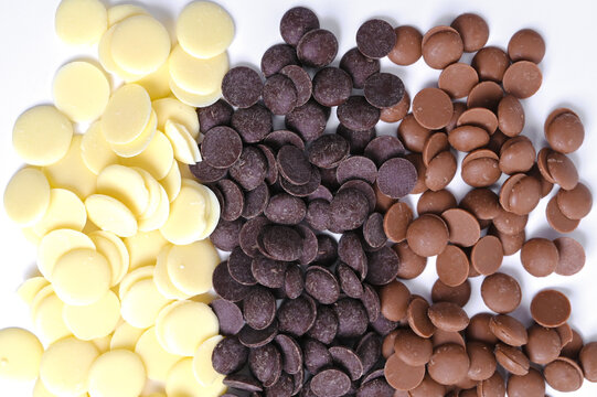 Texture of chocolate. Round chocolate callets for tempering and making homemade sweet desserts and decorations