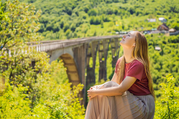 Montenegro. Woman tourist in background of Dzhurdzhevich Bridge Over The River Tara. Travel around...