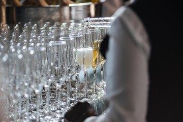 Waiter pouring champagne in stylish glasses at luxury reception, celebration.