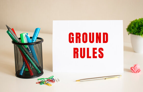 The text GROUND RULES is written on a white folded sheet of paper on the table. Nearby are pens and pencils.