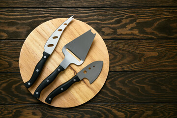 Cheese knife set on round cutting board, close-up, top view