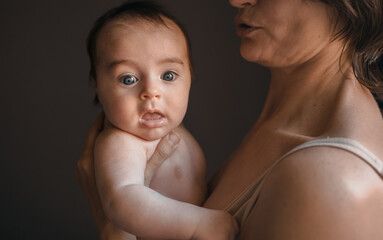 Mom, mummy, young mother with little baby daughter. Mum kissing and hugging child. Newborn cute happy girl smiling in woman hands. Happiness for parents in family. Aged parents, parenting, motherhood