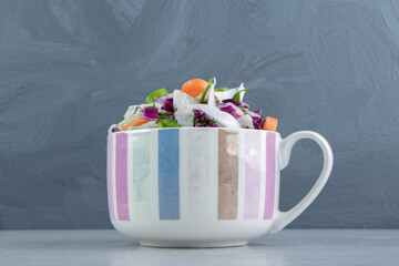 Various vegetables in the cup, on the marble background