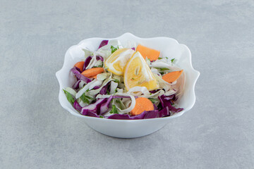 A plate of grated vegetables with lemon , on the marble background