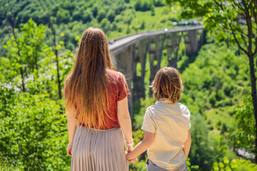Montenegro. Mom and son tourists in background of Dzhurdzhevich Bridge Over The River Tara. Travel...