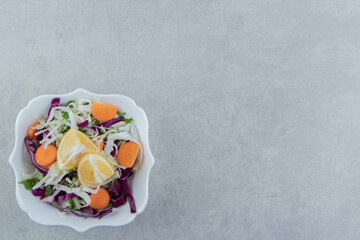 A plate of grated vegetables with lemon , on the marble background