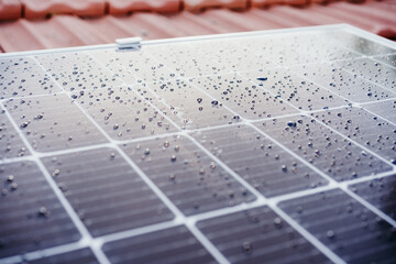 close up of water drops on solar panel on roof during sunrise.Renewable energies and green energy...
