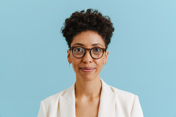 Young curly woman in eyeglasses smiling and looking at camera