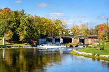Fototapeta na wymiar Old concrete dam along a river on a sunny autumn day