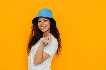 Naklejka premium White curly woman wearing panama smiling while rubbing her fingers