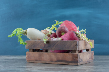 Red and white radishes in the box, on the marble background