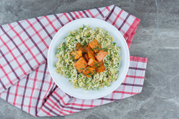  Rice and sliced carrots on plate, on the towel, on the marble background