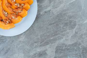 Pumpkin slices arranged in a row , on the marble background