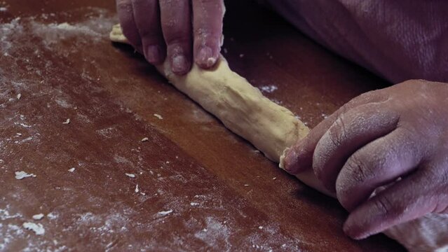 The hands of a Jewish woman forms blanks from dough for baking festive challah. Medium plan
