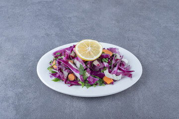 A plate of grated vegetables with lemon , on the marble background