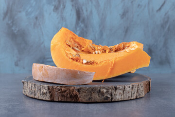 Pumpkin cut into pieces, on a board , on the marble background