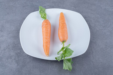 Two carrots in a plate , on the marble background