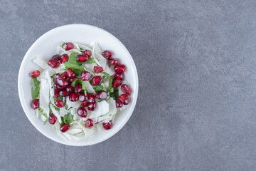 Pomegranate arils and grated vegetable, on the marble background