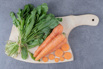 Watercress and carrots on the cutting board , on the marble background