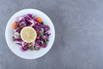 Grated vegetables with lemon on the plate, on the marble background