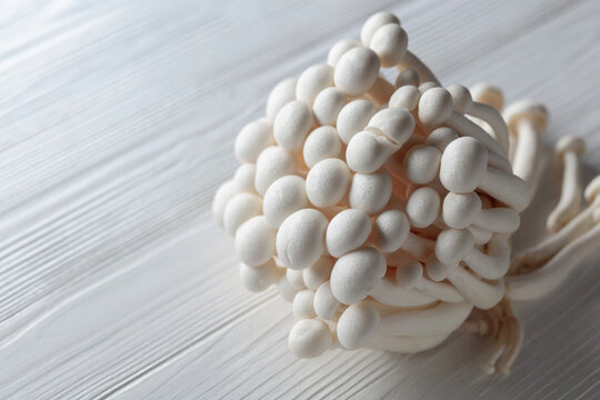 Bunch of Shimeji mushrooms on a white wooden table.