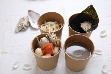 Seafood ramen soup ingredients in take-away boxes. Fish ramen components in carton containers on a...