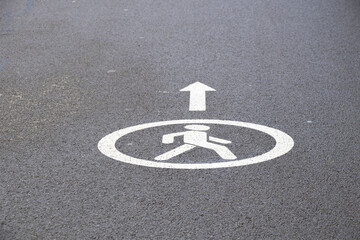 A pedestrian sign is drawn on the asphalt on the road, road