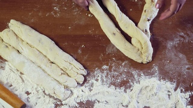 The hands of a Jewish woman weave challah dough with a pigtail for Shabbat with raisins. Medium plan