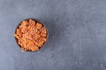 Uncooked heart-shaped pasta in wooden bowl