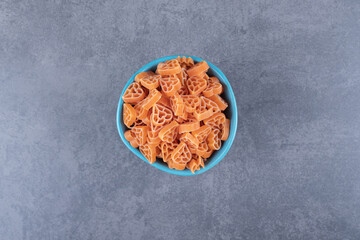 Dry heart-shaped pasta in blue bowl