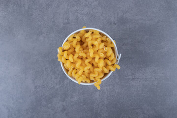 Raw elbow macaroni in metal bucket