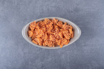 Raw heart-shaped pasta in ceramic bowl