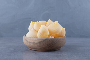Bunch of raw shell pasta in wooden bowl