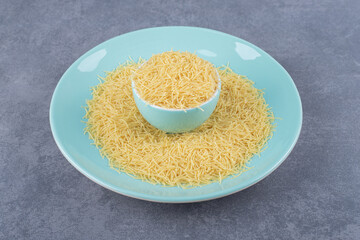 Heap of raw macaroni on blue plate