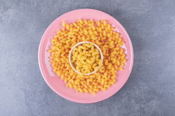 Raw dry macaroni on pink plate